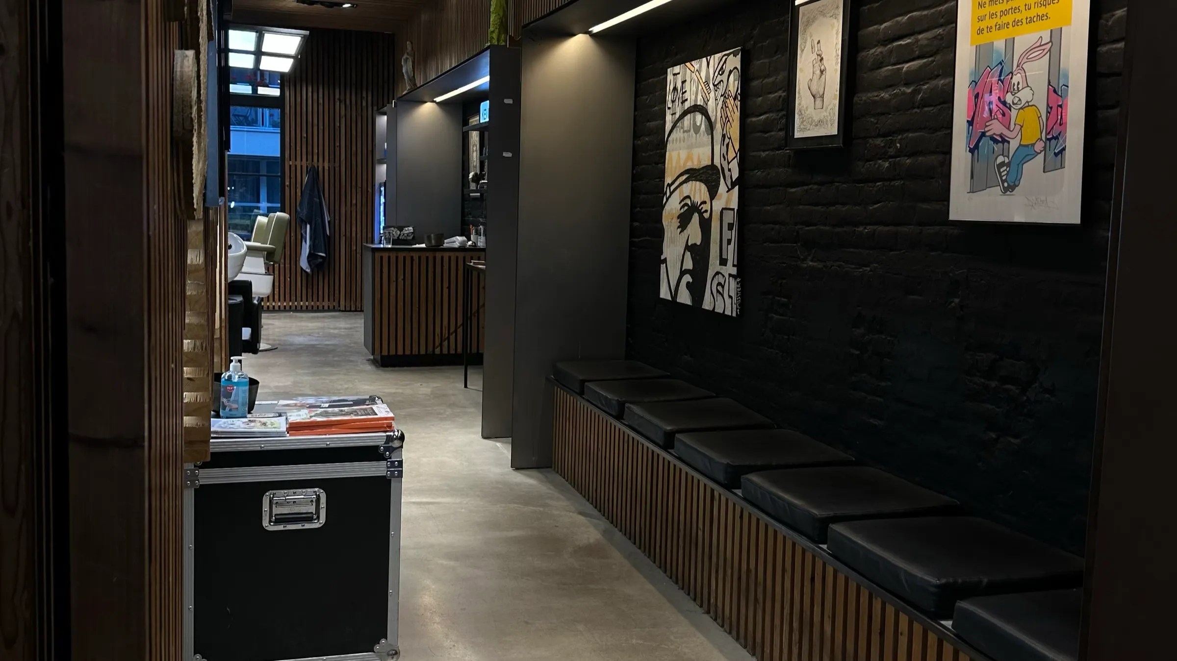 Banquette d'attente de BEAU devant un mur de brique noire et des portraits d'artistes locaux
